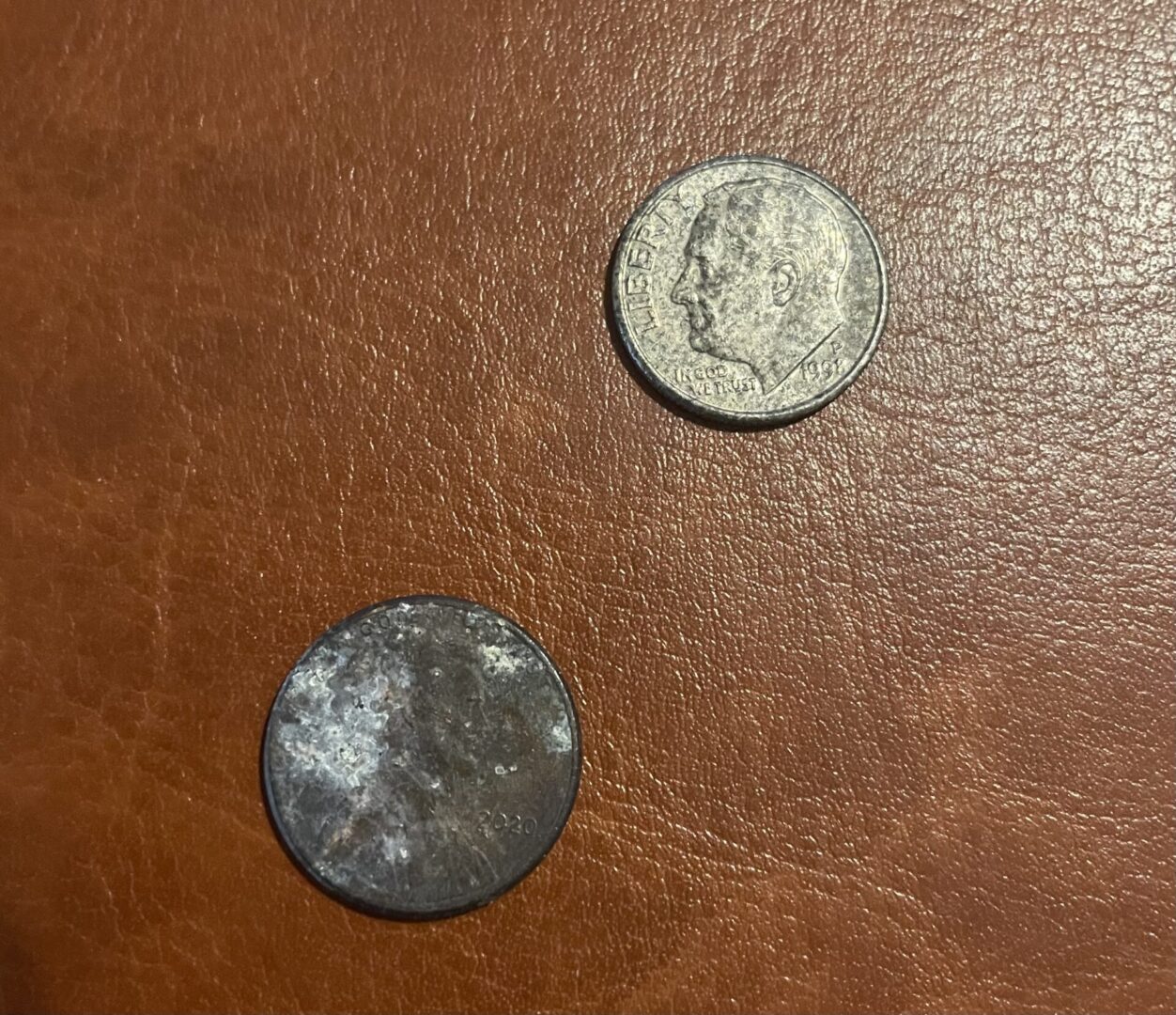 Two coins on a brown surface with one of them missing.